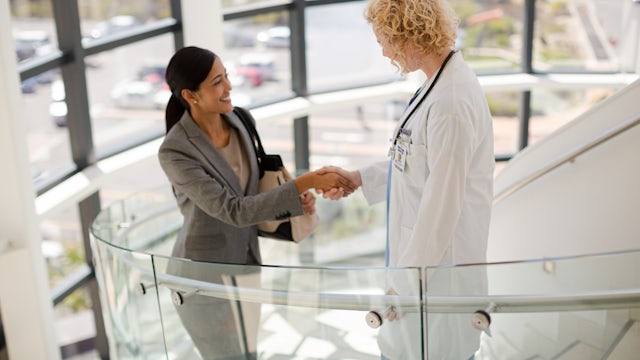 A doctor and a patient are shaking hands in a handshake.