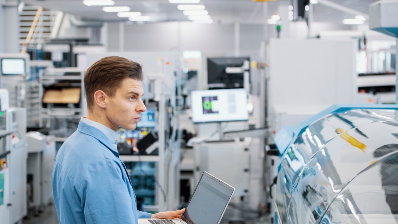 A worker checks a laptop on the shop floor.