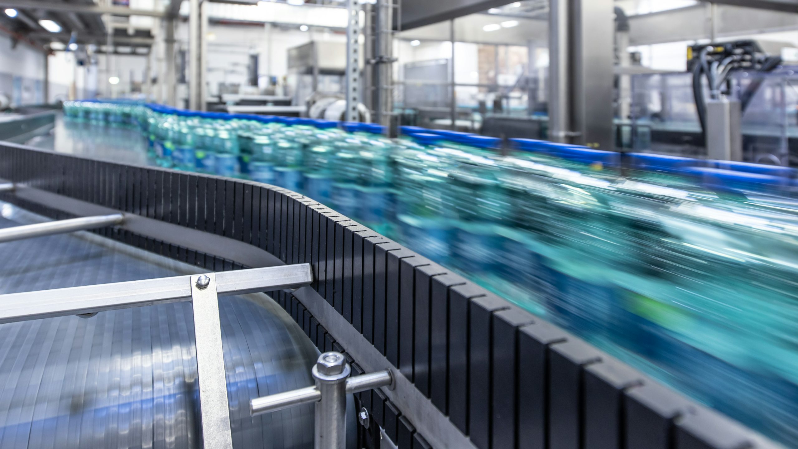 High‑speed beverage bottles on an automated conveyor in a modern food and beverage production line.