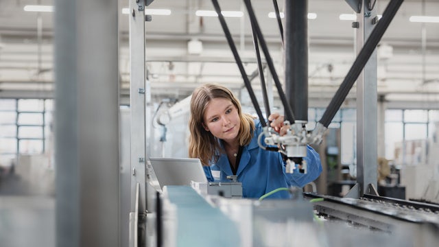 Technician inspecting a robotic system on a production line, showcasing advanced motion control in a modern manufacturing environment.