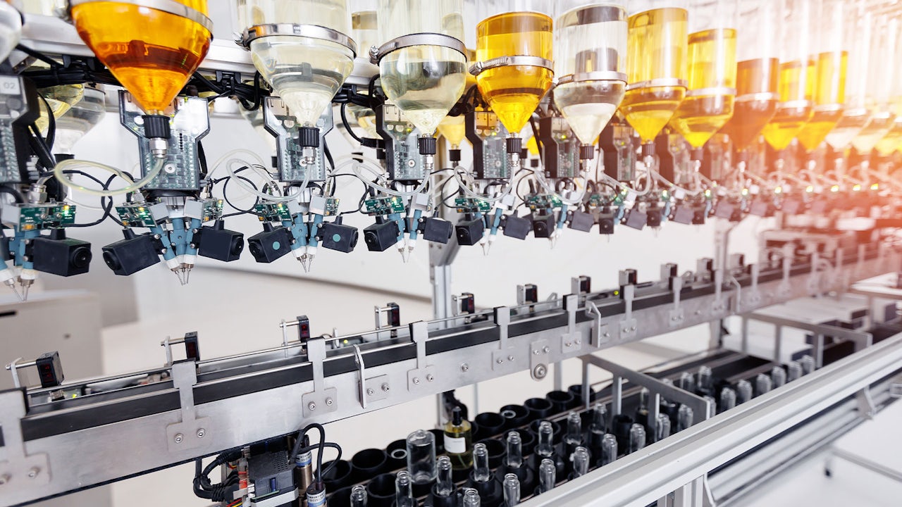 A factory floor with workers operating machinery and packaging products in a beauty and cosmetics manufacturing setting.