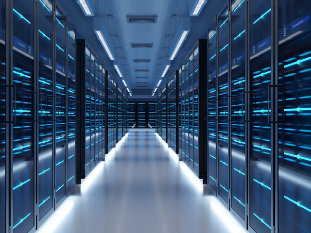A long, narrow server room with rows of black server racks on either side, illuminated by blue lights. The floor and ceiling are light grey, reflecting the blue light.