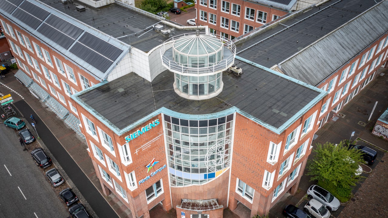 The image shows a group of people standing in front of a building with Siemens AG signage.