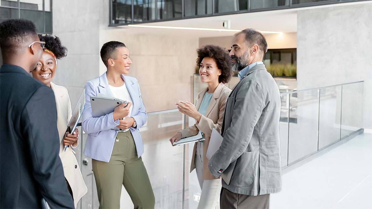 Group of colleagues standing in a circle smiling and talking.