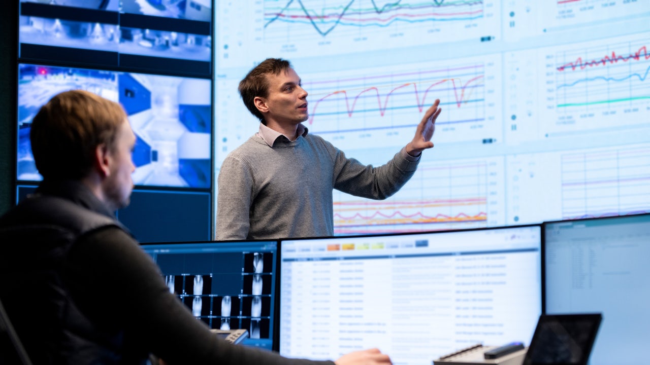 Two men looking at data on computer screens