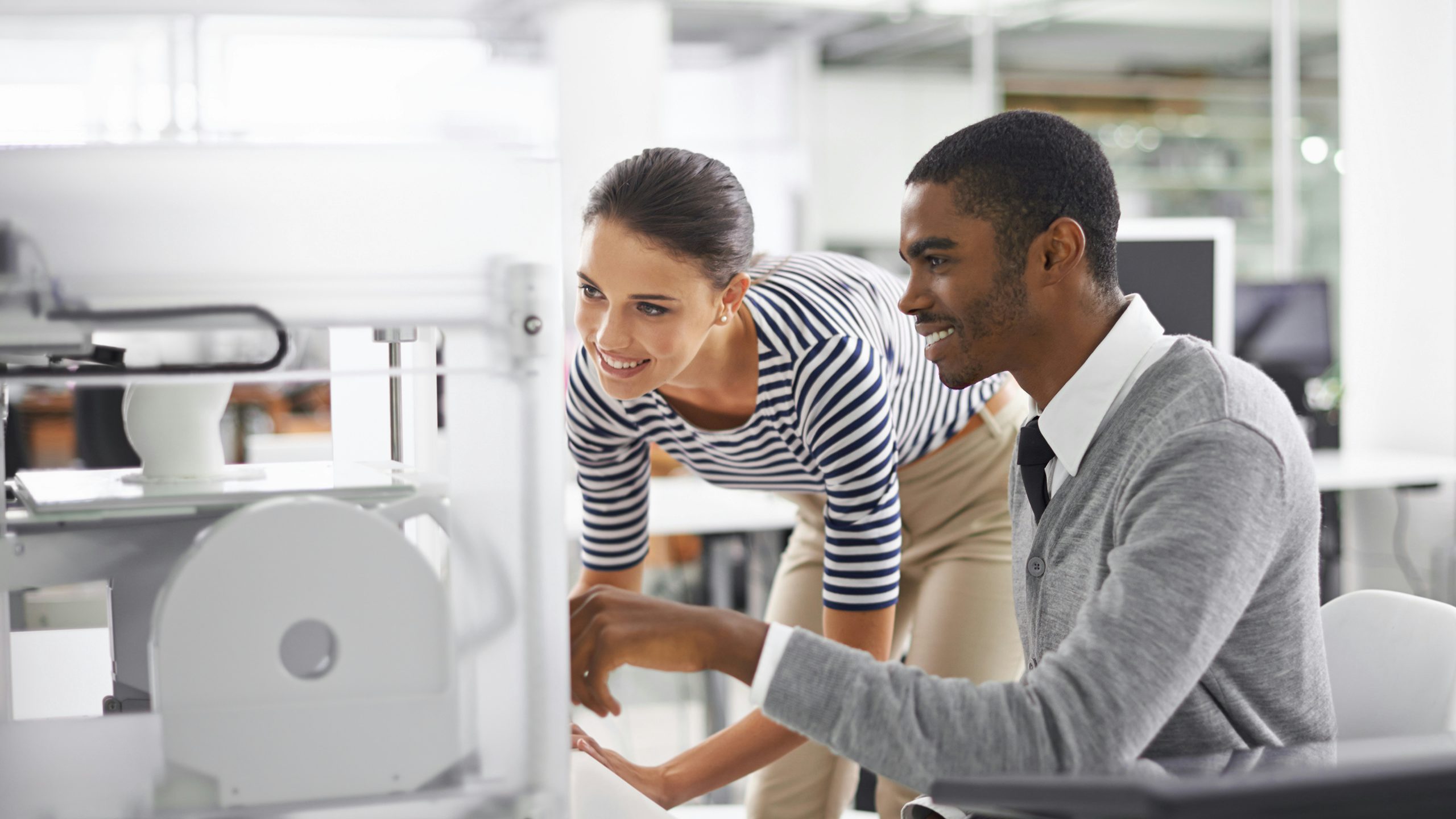 Two smiling people looking at a factory machine
