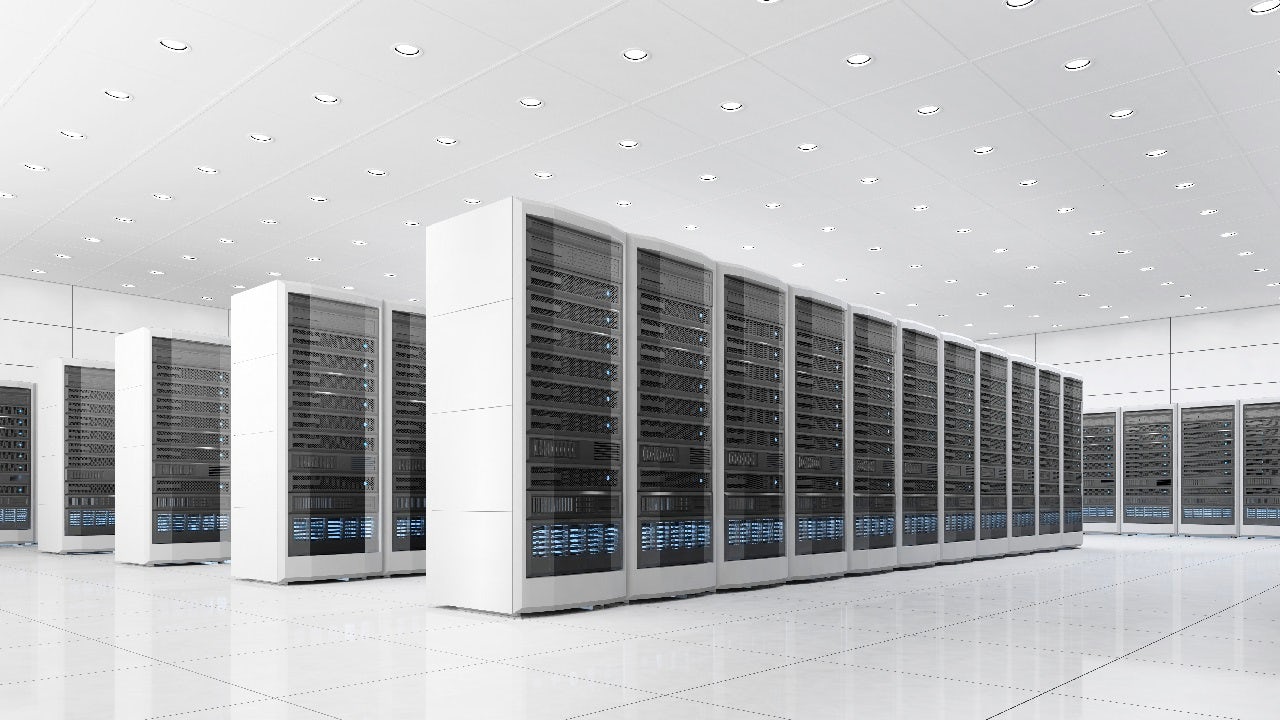 A wide shot of a pristine, white data center room with rows of black server racks extending into the distance.