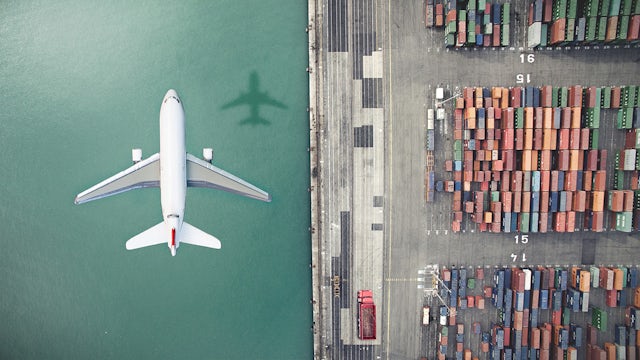Airplane overflying a container yard.