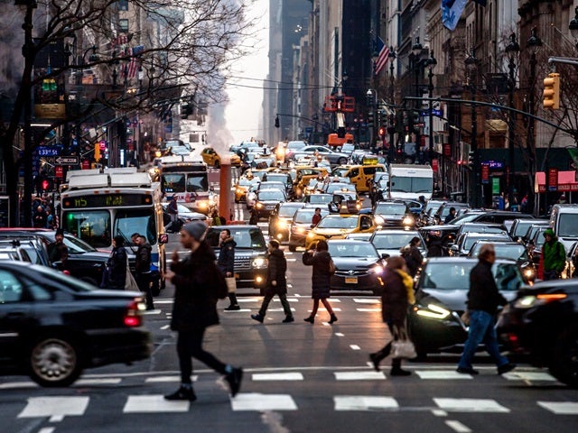 A photograph of a busy city road with heavy traffic and pedestrians crossing the street.