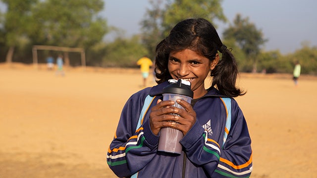 Child holds a shaker bottle with Blendhub’s powder-based food in a field.
