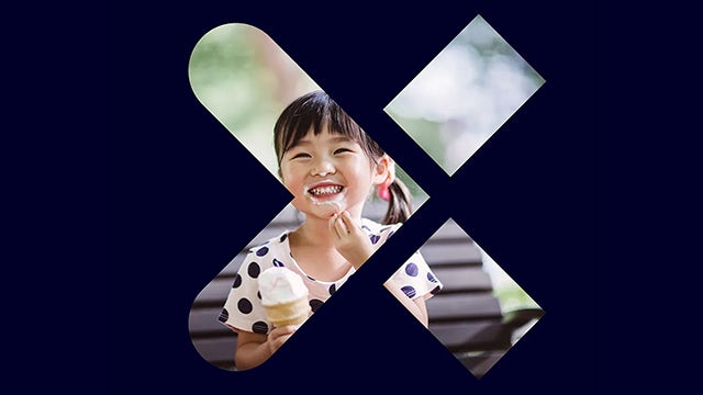 A young girl is holding an ice cream cone while standing in front of a bakery.
