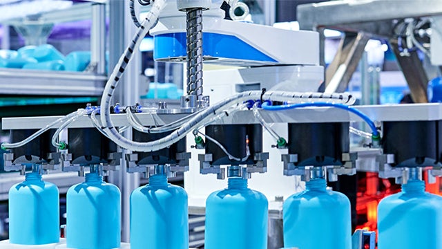 A factory with blue bottles and a machine in the background.