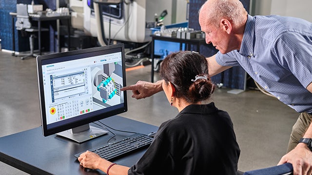 Man and woman working on a computer discussing simulation.