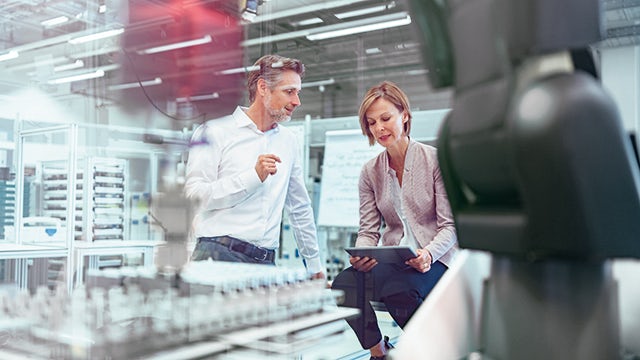 Two people working in a lab, looking at industrial IoT data on a tablet.