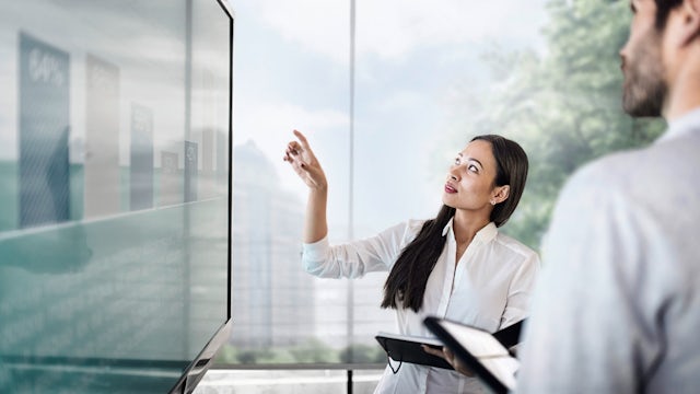 Businessman and businesswoman discussing finance in front of a screen with a graph.