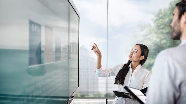 Businessman and businesswoman discussing finance in front of a screen with a graph.