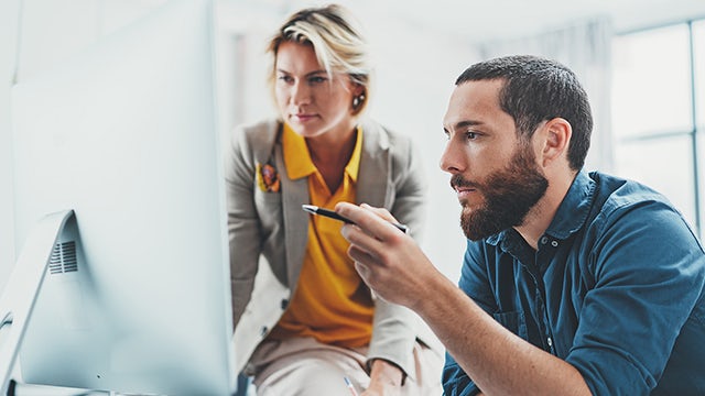 A man and a woman looking at a computer screen.