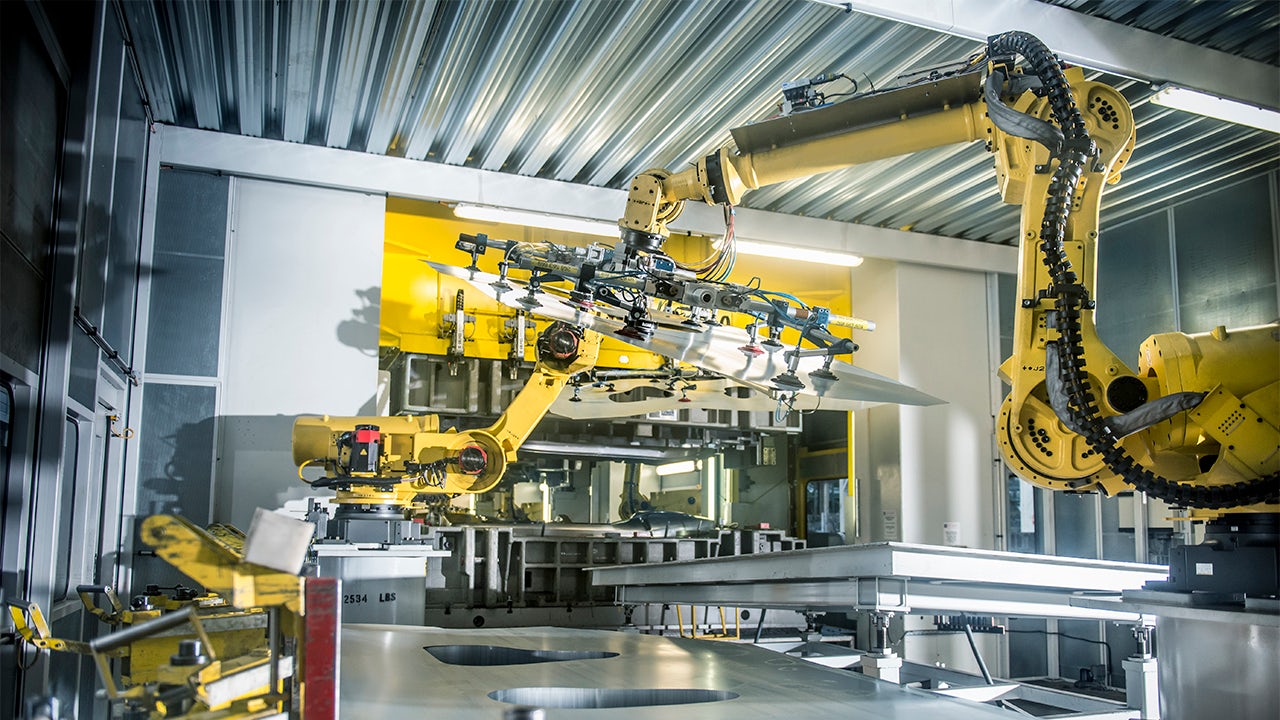 Robots handling car parts in a factory setting.