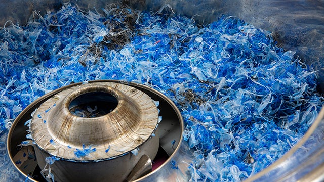 A blue plastic recycling process with a machine processing plastic waste.