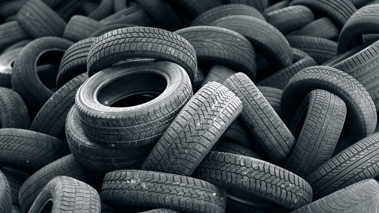 A tyre recycling facility with a large pile of tyres and plant in the background.
