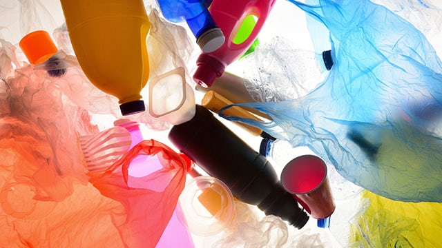 Colourful plastic bottles, bags, cups and food containers float in water.