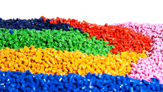 Plastic pellets in a pile organised by bright primary colours. 