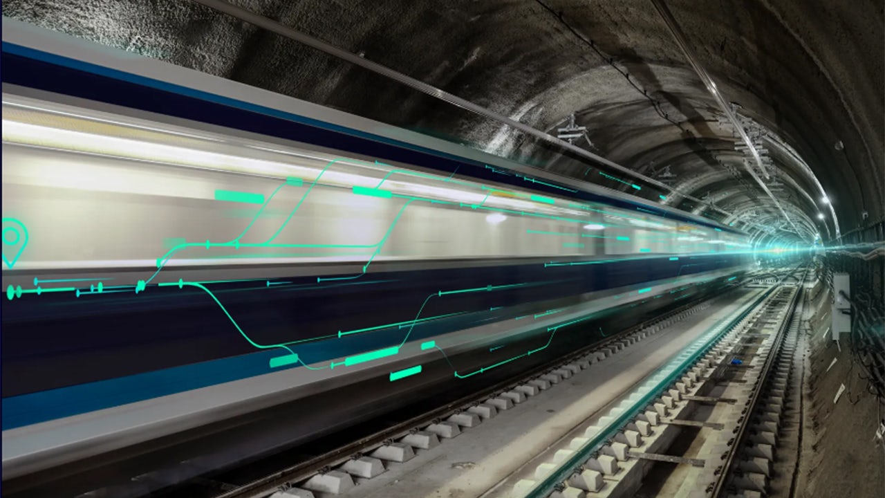 A train traveling on a track with a city skyline in the background.