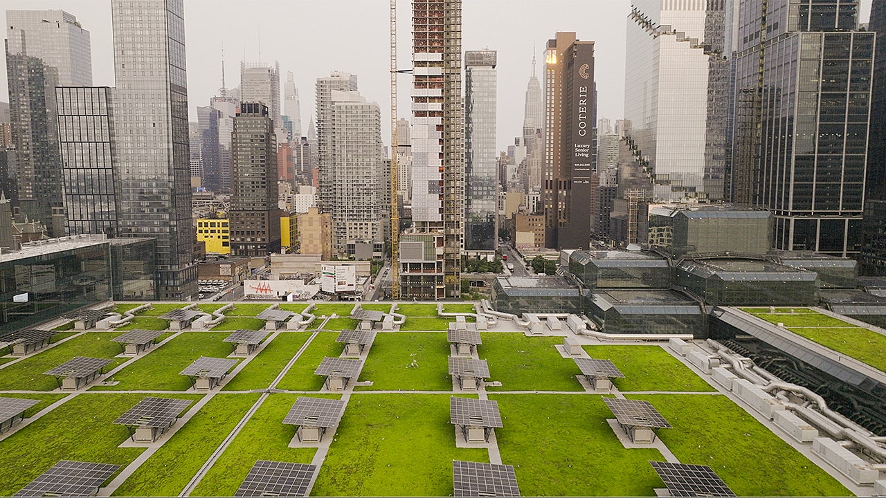 A group of people are collaborating on a project in a modern conference room at the Javits Center.