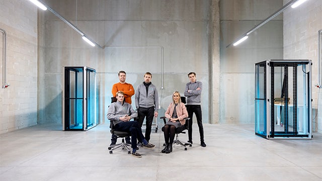 Five people gathered in a large data centre.   