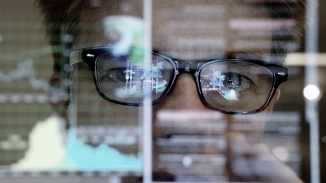 A man in glasses is analyzing digital logistics on a computer screen.