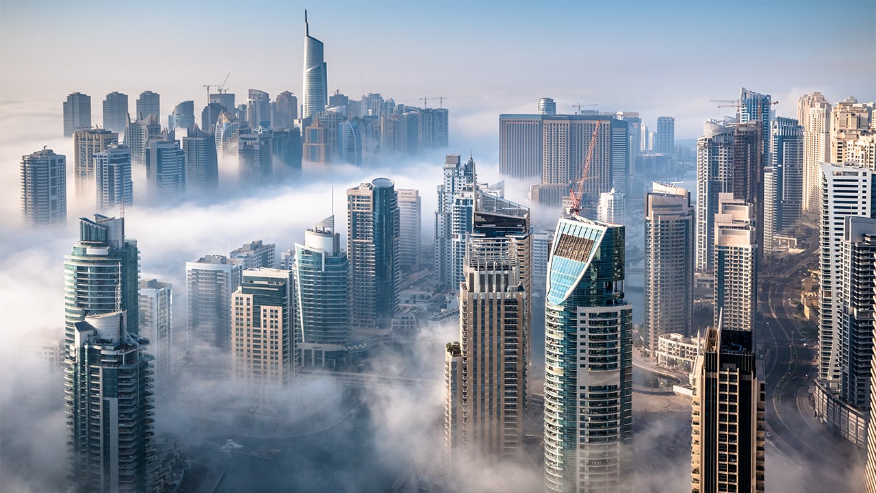 Dubai skyline at night with illuminated buildings and a clear sky.