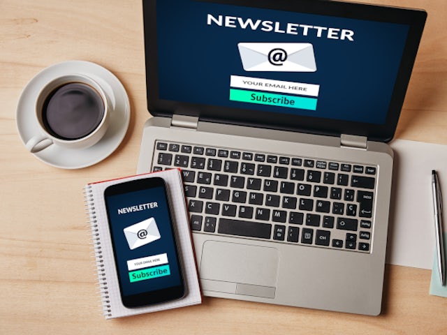 Laptop and smartphone displaying a newsletter subscription screen on a desk, promoting email sign‑up and digital communications.