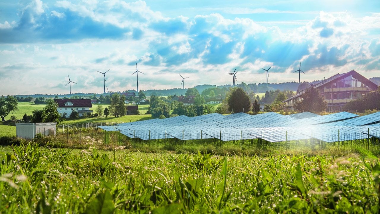 Solar panels and modern wind mills in green field.