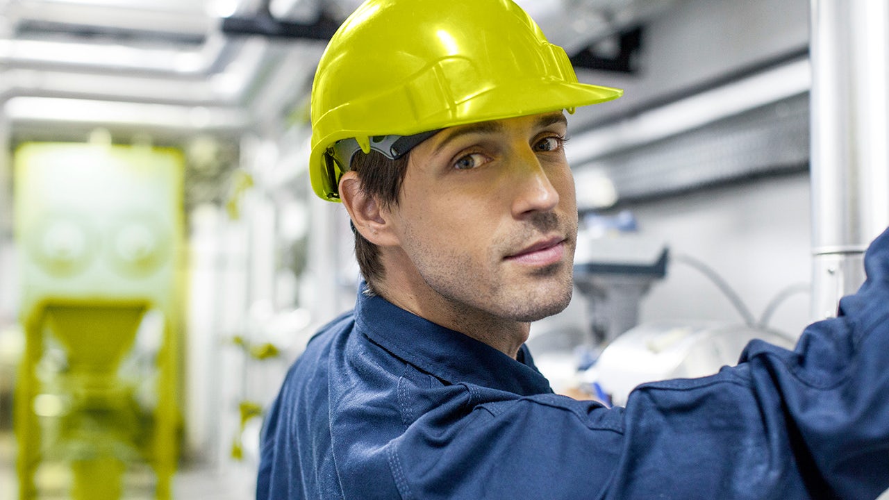 A worker in a factory is operating a machine, possibly involved in the production of fertilizer.