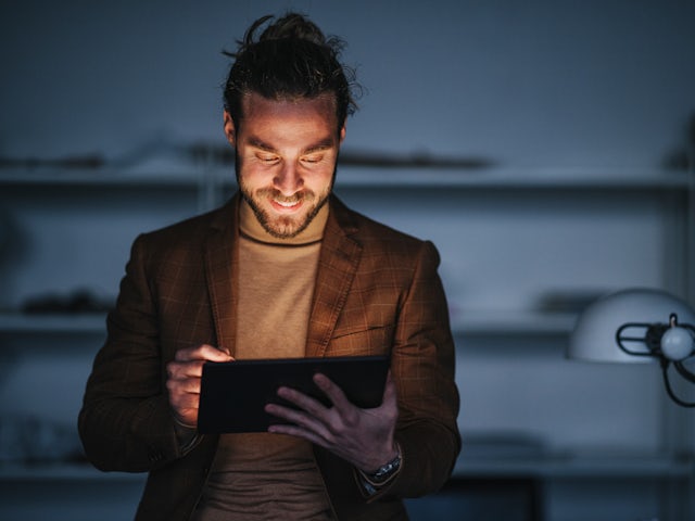 Man smiling and working in a tablet.