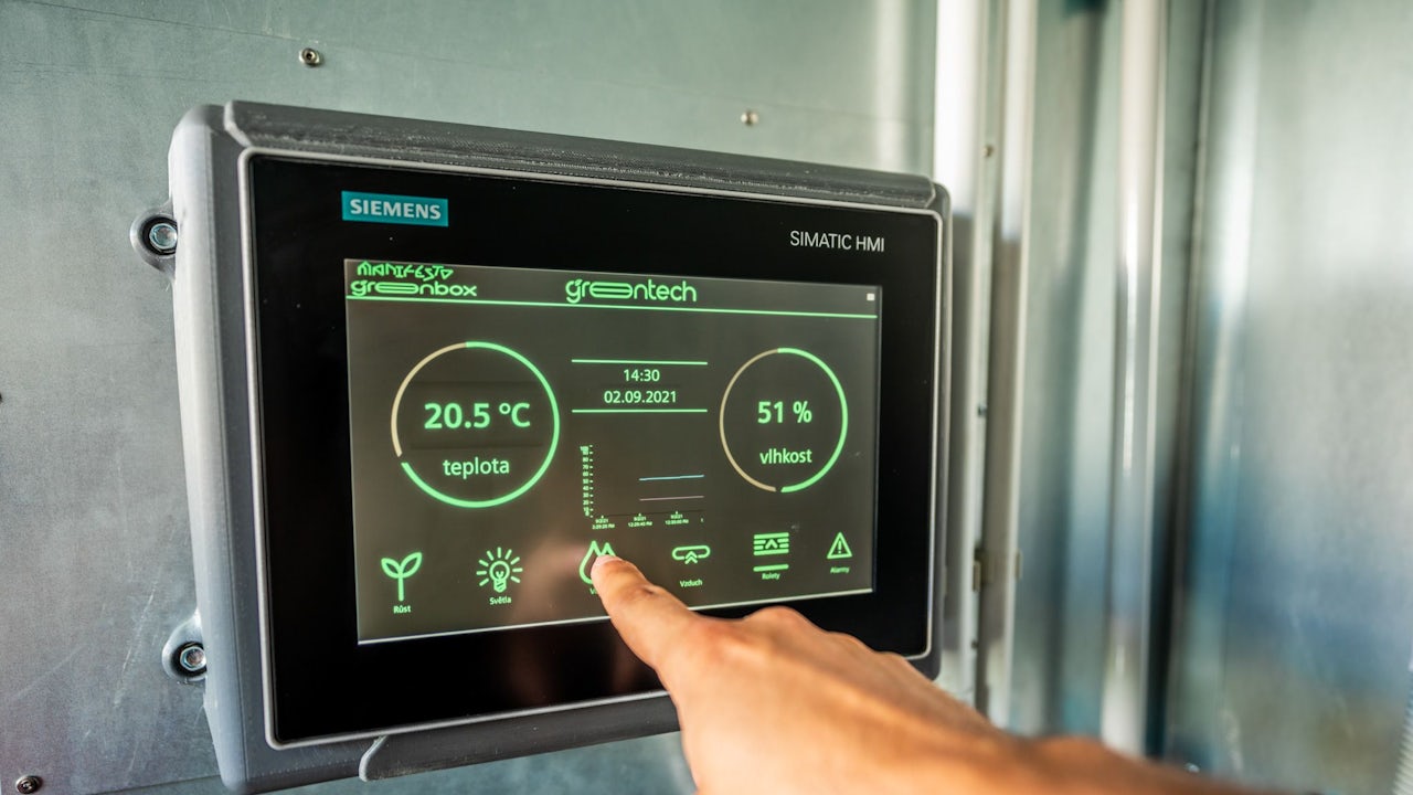 A man is using a touchscreen interface on the Siemens GreenTech HMI unified comfort panel.