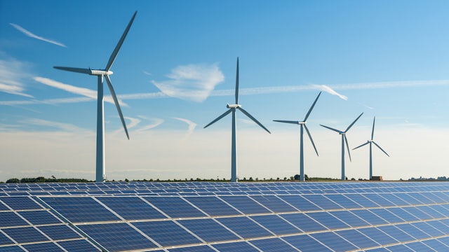 Wind turbine energy generaters on wind farm, with solar panels underneath.