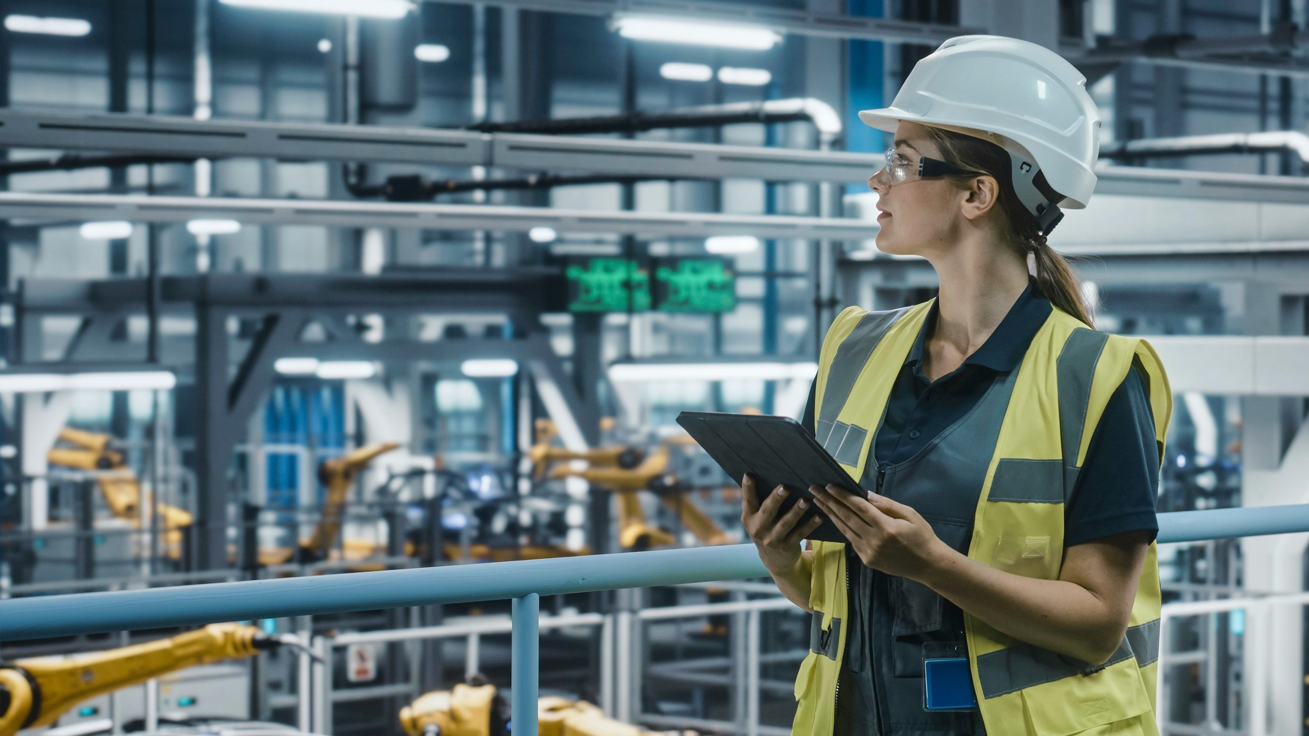 Woman in a manufacturing facility holding a tablet.