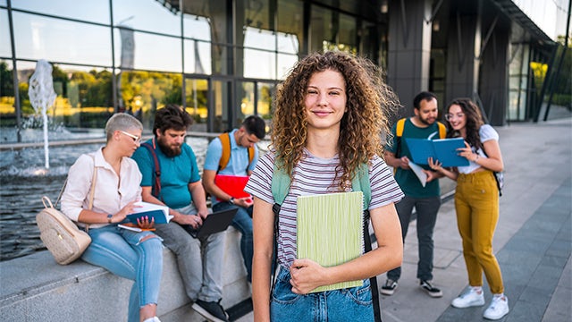 A girl is standing in front of a group of students, possibly giving a lecture or presentation.
