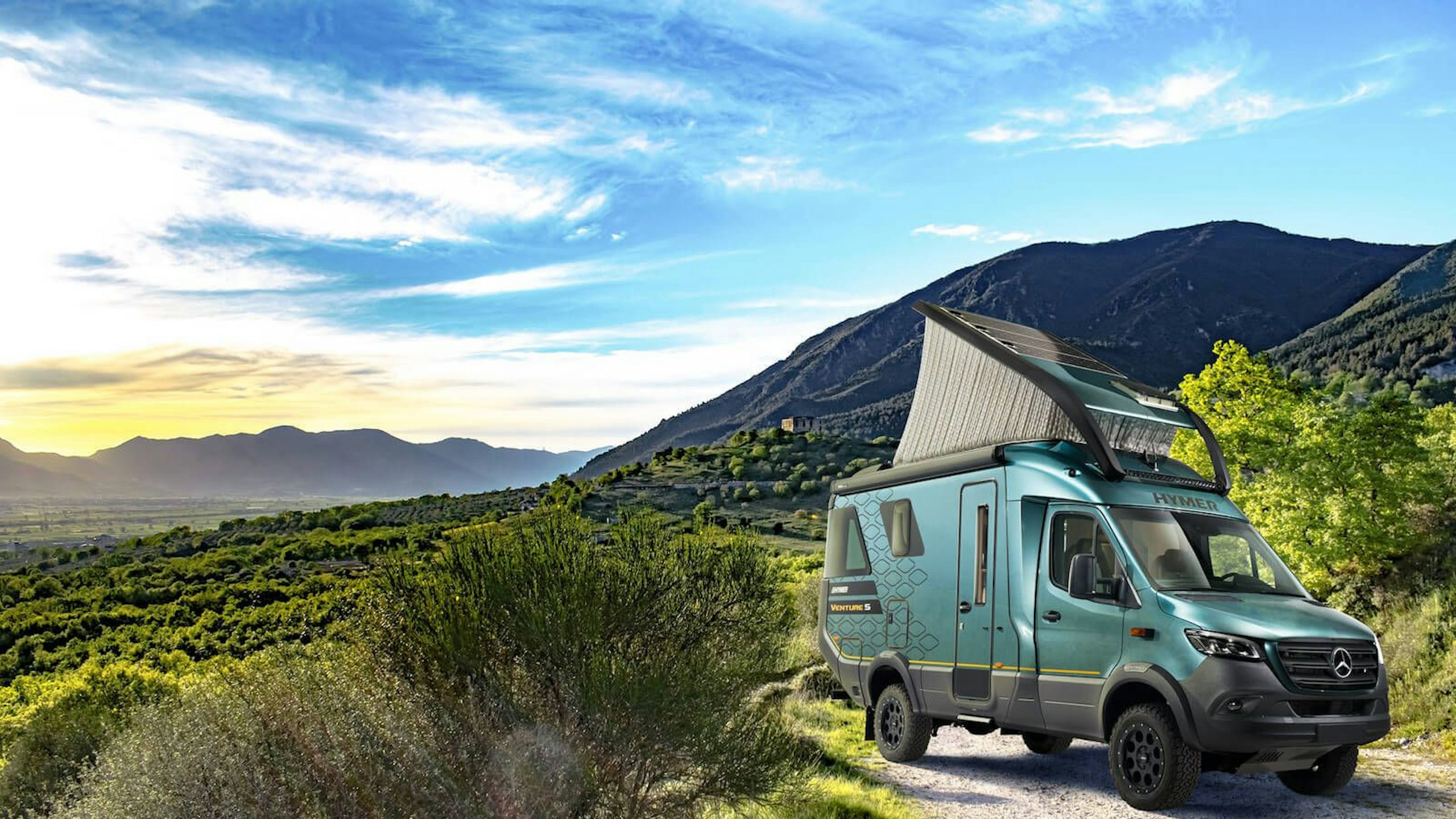 A landscape image of a Hymer Vemture S van parked in a scenic outdoor area with mountains in the background.