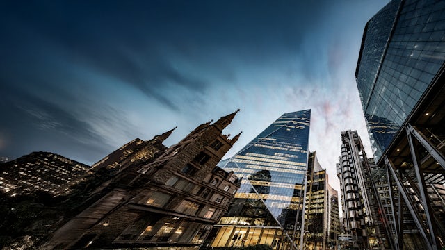 A cityscape of London with a prominent building in the foreground and a clear blue sky.