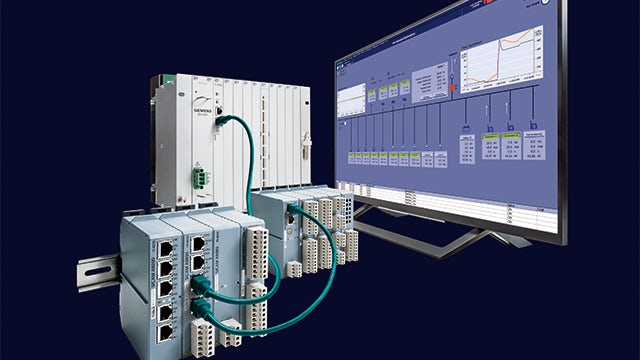Siemens industrial control units connected by green cables to a monitor displaying data and graphs, on a dark background.