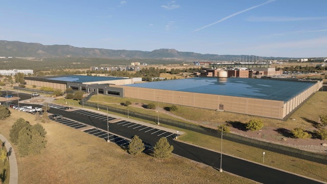 A drone photo of a Siemens facility with a large building and a field in the background. 