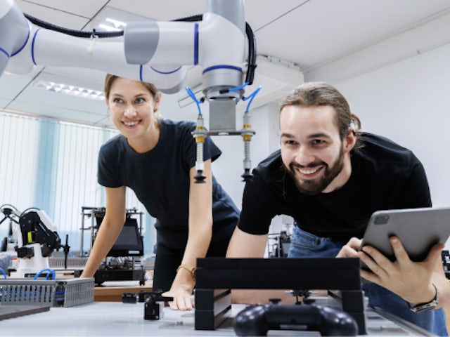 Woman and man in a lab looking at robotic arm