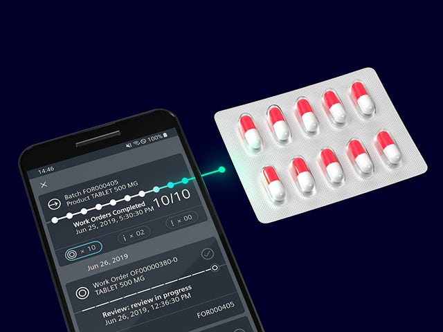 A cell phone next to a blister sheet full of pill capsules