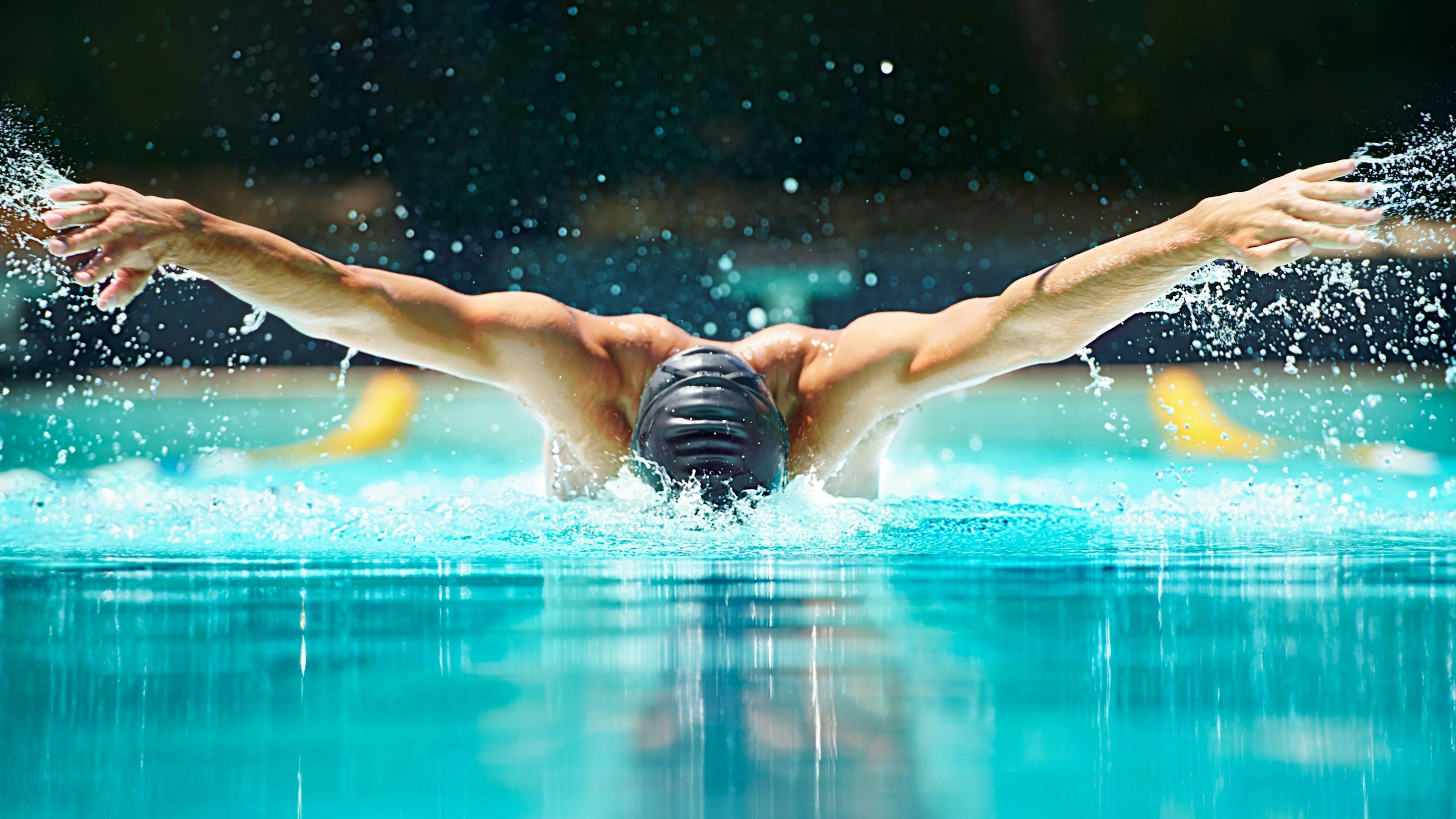 A person is swimming in a pool using the butterfly stroke. 