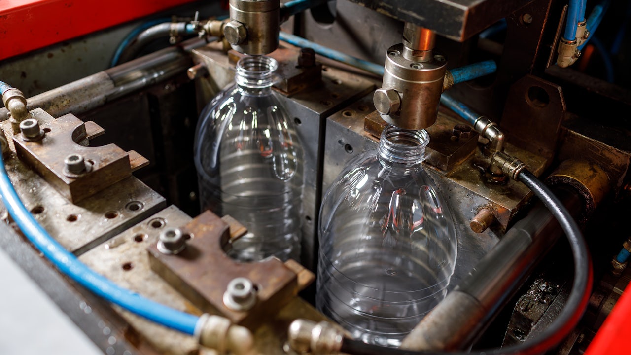 A plastic machine is blowing and forming a plastic product in a factory.