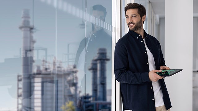 Man holding tablet device while looking out the window.