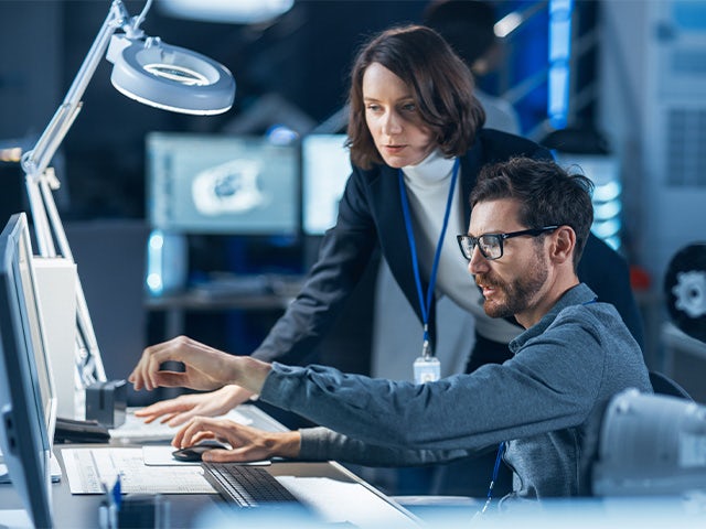 Two engineers looking at a computer while reviewing a medical device design.