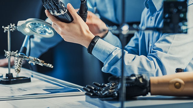Engineer holding a prosthetic robot arm.